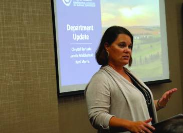 Woman standing in front of projector screen.